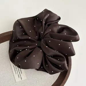 Close-up of brown satin scrunchie with sparkling rhinestones on an elegant background