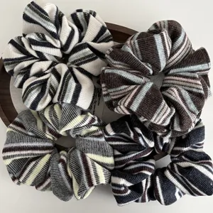 Detailed texture of four-piece set of knitted striped scrunchies on a wooden tray