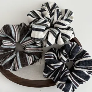 Close-up of three knitted striped hair scrunchies on a decorative wooden tray
