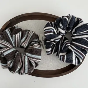Close-up of two knitted striped scrunchies in coffee and navy blue on a wooden tray