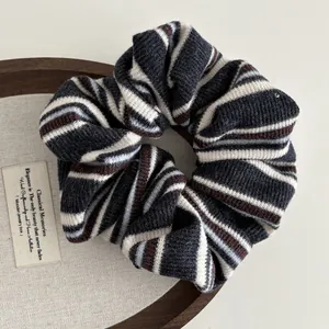 Detailed close-up of knitted striped scrunchie with soft fabric texture on a wooden tray