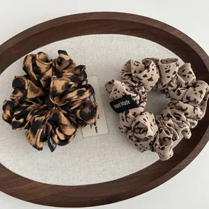 Close-up of leopard print fabric scrunchies with Hand Made label on a wooden tray