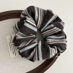 Detail of retro knit scrunchie with brown and blue stripes on a wooden tray