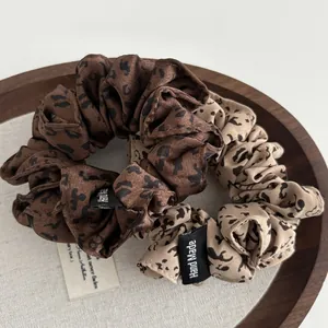 Close-up of leopard print scrunchies in deep coffee and khaki on a wooden tray