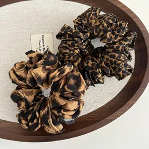 Detailed close-up of leopard print scrunchies with handmade labels on wooden tray