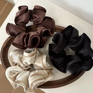 Detalle de coleteros de terciopelo en negro, marrón y beige con una textura brillante