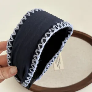 Navy blue fabric headband featuring light blue hand-stitched knitted yarn edging