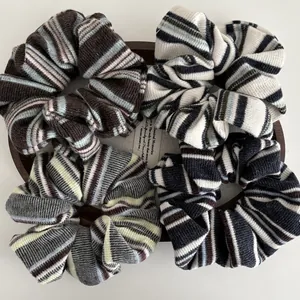 Set of four striped knitted hair scrunchies in earthy tones on a rustic wooden tray
