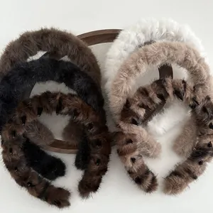 Plush wavy headbands in assorted neutral colors on a vintage wooden tray for hair styling