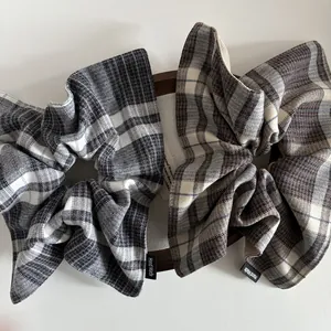 Detailed view of plaid wool scrunchies with Hand Made woven labels in a wooden tray
