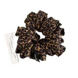 Handmade leopard print fabric hair scrunchie with a woven tag on a clean white background