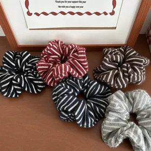 Set aus fünf gestreiften Strick-Haargummis in Winterfarben auf einem Holztisch