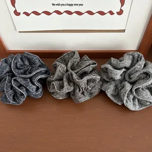 Detailed texture of three thick knitted scrunchies in grey and coffee tones
