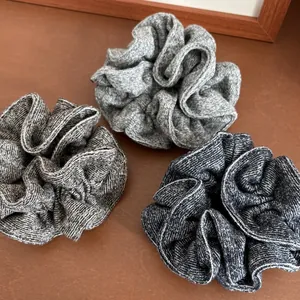 Close-up of three knitted scrunchies in shades of grey on a wooden background
