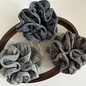 Close-up of soft knit scrunchies set in navy blue, gray and brown on a wooden tray