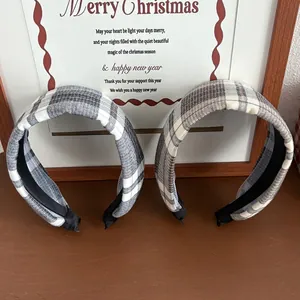 Close-up of two padded plaid headbands in grey and beige tartan fabrics for winter