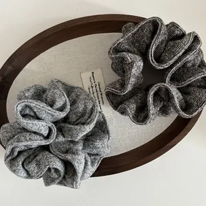 Close-up of soft knit scrunchies in gray and brown on a rustic wooden tray decor