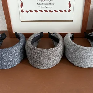 Three-piece set of wide knitted tweed headbands in gray tones on a wooden surface