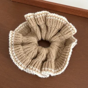 Gros plan d'un chouchou en tricot kaki avec bordure en dentelle blanche sur bois