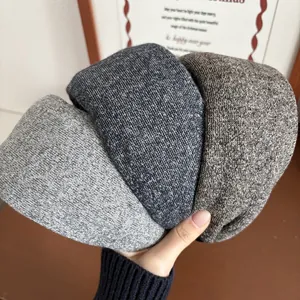 Close-up of three thick knitted headbands in grey blue and brown for autumn winter style