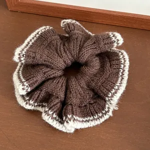 Gros plan d'un chouchou en maille marron avec bordure en dentelle blanche sur bois