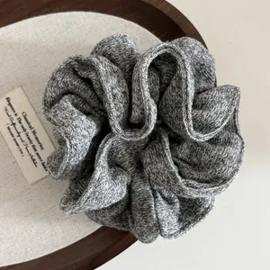 Close-up of grey knitted scrunchie with soft woven texture on a wooden tray