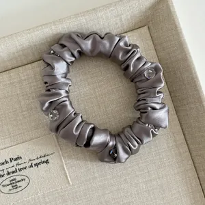 Detail of silver grey satin hair scrunchie with sparkling crystal beads on a tray