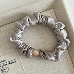 Detail view of satin hair scrunchie with crystal beads and metallic champagne sheen