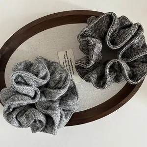 Set of two soft knit grey oversized scrunchies displayed on a rustic wooden tray