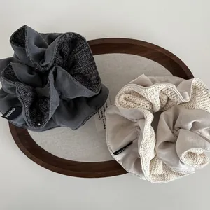 Minimalist knit hollow scrunchies in grey and beige with Hand Made labels on a wooden tray
