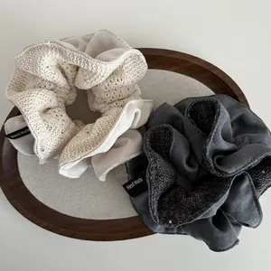 Off-white and dark grey knitted hollow hair scrunchies on a wooden tray with handmade label