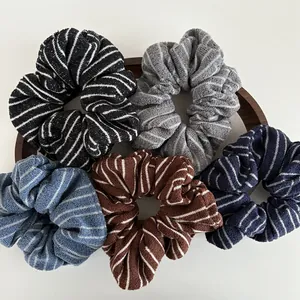 Five striped knit scrunchies in varied colors on a wooden tray with a white background