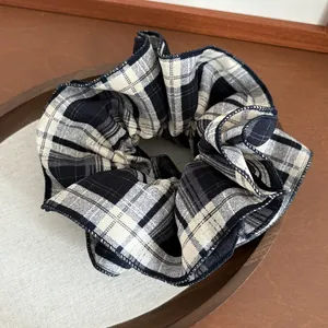 Plaid checkered oversized hair scrunchie in blue and brown on a wooden tray