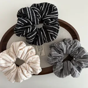3-piece set of striped knit scrunchies in black grey and beige on a wooden tray