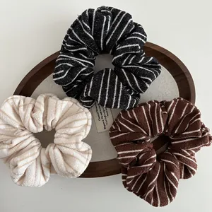 Detailed view of striped knit hair scrunchies in black, cream, and brown soft fabric