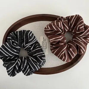 Striped knit scrunchie set in black and brown, soft fabric hair ties on a wooden tray