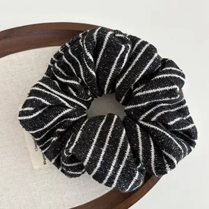 Detailed view of striped knit scrunchie texture on a wooden tray for hair styling