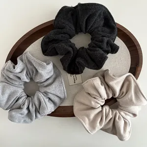 Three-piece set of knitted wool scrunchies in grey and beige tones for bun hairstyles