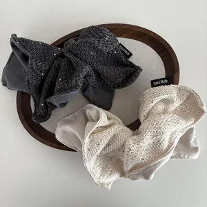 Gebreide tweekleurige scrunchies in grijs en beige met zilveren pailletten en label
