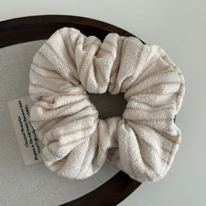 Macro shot of a soft striped knit scrunchie on a vintage wooden tray background