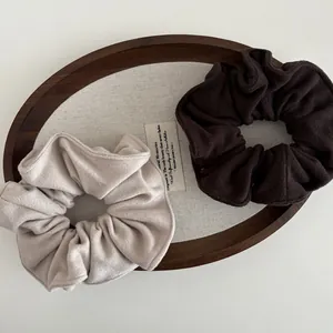 Set of beige and dark brown wool scrunchies for hair ties in a wooden tray