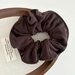 Detail of dark brown wool fabric scrunchie with soft brushed texture and pleated design