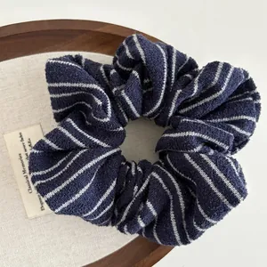 Detail of soft striped knit scrunchie texture in dark blue and white on a wooden tray