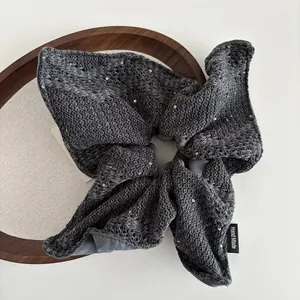 Detail van donkergrijze gebreide scrunchie met pailletten en Hand Made-label