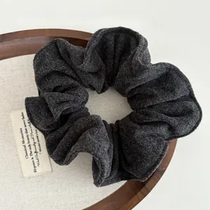 Detailed macro view of dark grey wool fabric texture on a soft oversized scrunchie hair tie