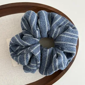 Close-up of soft navy and grey striped knit scrunchie on a wooden tray with linen lining
