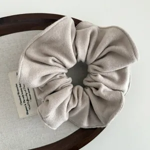 Detail of beige soft wool fabric hair scrunchie with fine stitching and textured finish