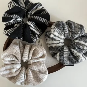 Dettaglio di elastici scrunchie in maglia fatti a mano in colori neutri su vassoio in legno