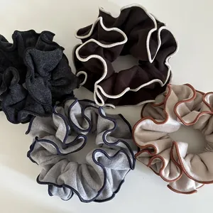 Detail of wool fabric hair scrunchies with contrast stitch edging in neutral tones