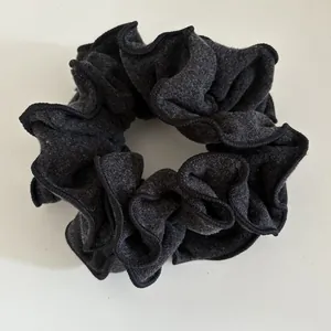 Detailed view of dark grey wool fabric scrunchie with thick texture and black overlock edges